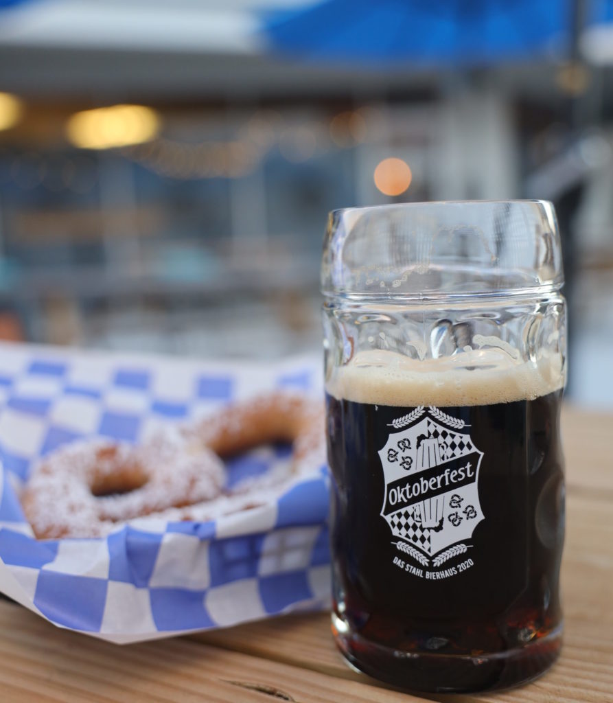 German stein full of beer along side a soft pretzel